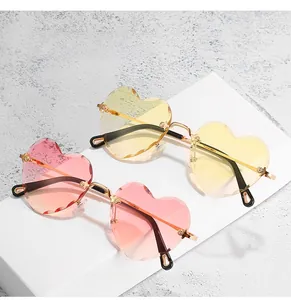 Close-up of heart-shaped rimless sunglasses with pink and yellow lenses and wavy edges