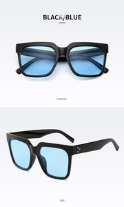 Detail of black square frame sunglasses with blue lenses and golden rivets accents