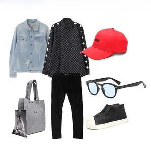 Flat lay of trendy denim jacket, polka dot shirt, red cap, and retro sunglasses outfit set