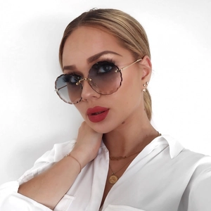 Detail of rimless flower-shaped blue gradient sunglasses on model with gold temples