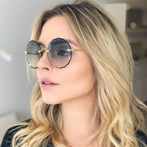 Close-up of rimless sunglasses with wave-cut gradient lenses and gold metal temples