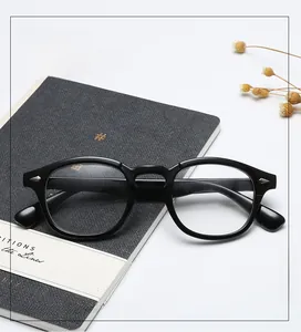 Close-up of black retro full-rim glasses frame with metal rivets on a textured notebook