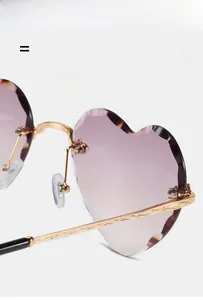 Detail of rimless heart-shaped sunglasses with purple gradient lenses and gold metal temples