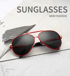 Close-up of red metal aviator sunglasses with dark lenses on a stone base