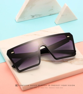 Detail of square oversized sunglasses with purple gradient lenses and gold accents
