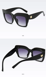Detail view of square black sunglasses with purple gradient lenses and gold accents