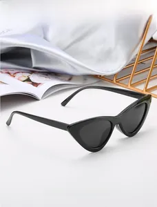 Détail des lunettes de soleil œil-de-chat noires brillantes avec verres foncés sur satin