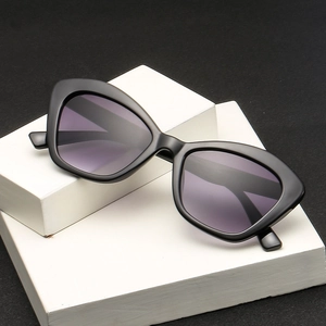 Stylish cat eye sunglasses with thick black frames and dark purple lenses on white stone