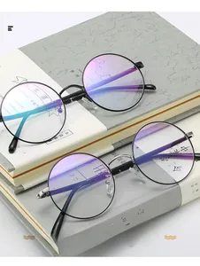 Gros plan de lunettes rondes vintage en métal avec filtre anti-lumière bleue sur livres