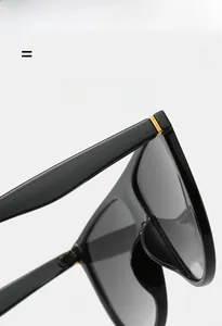 Détail de lunettes de soleil noires avec charnière en métal doré et monture en résine
