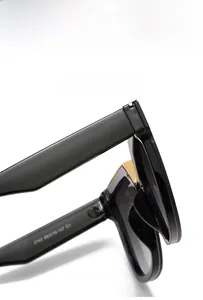 Détail de lunettes de soleil carrées avec monture en métal et charnières dorées