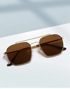 Close-up of golden double-bridge sunglasses with brown lenses and tortoiseshell temple tips