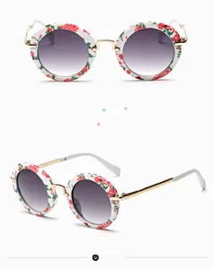Details einer runden Kinder-Sonnenbrille mit Blumenmuster und Metallbügeln in Gold