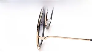Détail de lunettes de soleil rondes en métal doré avec verres dégradés gris et plaquettes