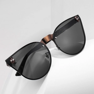 Lunettes de soleil œil-de-chat gothiques avec crâne en bronze sur marches blanches