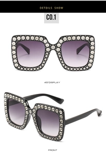 Detail einer quadratischen übergroßen Sonnenbrille mit Strassbesatz und violetten Verlaufsgläsern