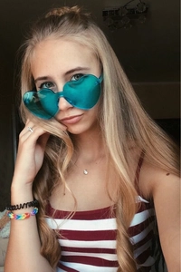 Détail d'une jeune femme portant des lunettes de soleil sans monture en forme de cœur sarcelle