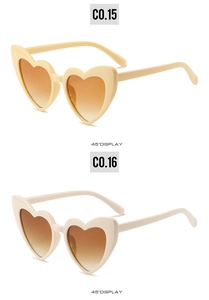Dettaglio occhiali da sole a forma di cuore con montature beige e lenti sfumate