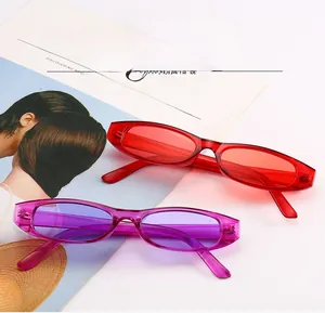 Retro small oval sunglasses in bright red and transparent purple colors on a magazine