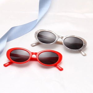 Oval alien sunglasses in bright red and grey marble textures on silk background