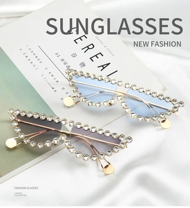 Détail de lunettes de soleil œil-de-chat strassées avec monture dorée sur soie