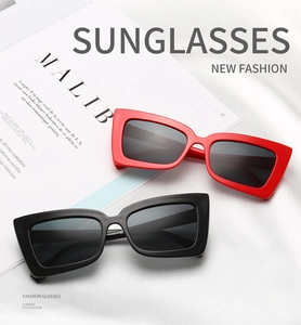 Detail of red and black rectangular sunglasses on silk and a Malibu magazine background