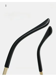 Detail macro view of sleek black rimless sunglasses temple with premium gold metal hinges