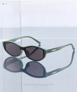 Detail of dark green cat-eye sunglasses with silver metal temples on a reflective surface