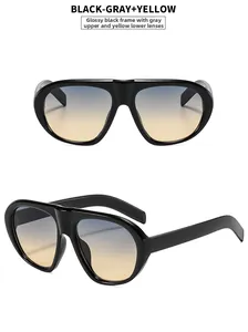 Detail of oversized black sunglasses with gradient gray to yellow lenses in a retro style