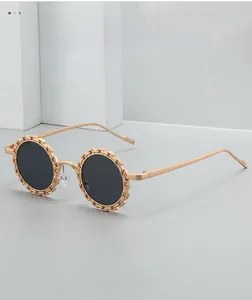 Détail de la monture dorée ronde de lunettes de soleil avec texture chaîne tressée