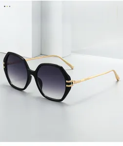 Détail de lunettes de soleil hexagonales avec monture noire et branches dorées