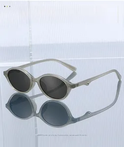 Detail of grey translucent oval sunglasses with dark lenses on a textured glass surface
