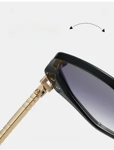 Détail de la charnière en métal doré texturé et de la monture noire polie des lunettes