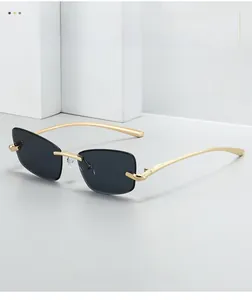 Détail de lunettes de soleil œil-de-chat sans monture avec verres gris et branches dorées