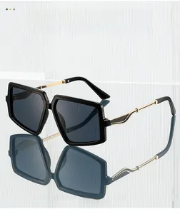 Detail of oversized square sunglasses featuring hollow gold metal temples and dark lenses