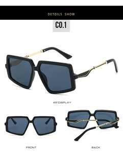 Detail view of large geometric sunglasses with black frames and wavy gold metal temples