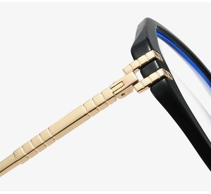 Macro view of gold metal hinge and blue light blocking lens on black polygon frame