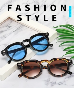 Detail of round vintage sunglasses with silver stud rivets and colorful lenses on marble