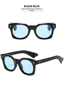 Détail de lunettes vintage avec monture noire, verres bleus et rivets dorés fléchés