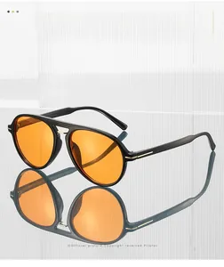 Detail of pilot sunglasses with orange lenses, black frame and golden metal accents
