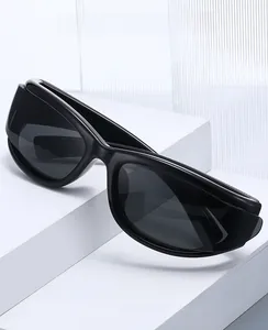 Détail des lunettes de protection Y2K noires sur un support géométrique blanc