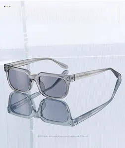 Vue détaillée de lunettes de soleil rectangulaires grises sur une surface réfléchissante