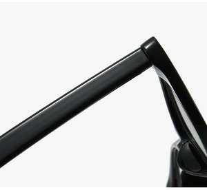 Macro detail of glossy black cat-eye eyeglass frame hinge and premium texture finish