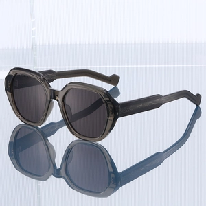 Polygonal grey transparent sunglasses with dark lenses and wavy temple detail on blue base