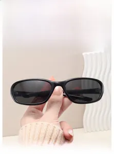 Close-up of Y2K style wrap sunglasses featuring a black frame and gray lenses on display