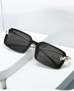 Détail de lunettes de soleil carrées noires avec branches en métal à maillons dorés