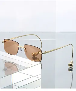 Makro-Detailansicht der randlosen braunen Gläser mit goldenen Bügeln und Goldkugeln