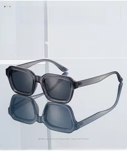 Close-up of square translucent grey sunglasses on reflective surface with glass backdrop