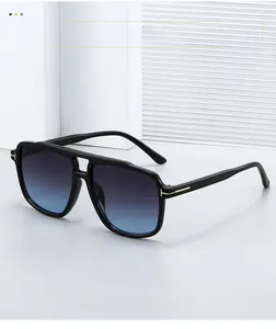 Close-up of black aviator sunglasses with gold T-shaped metal hinges and blue lenses