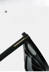 Detail showing the golden metal hinge and texture of the black eyewear frame